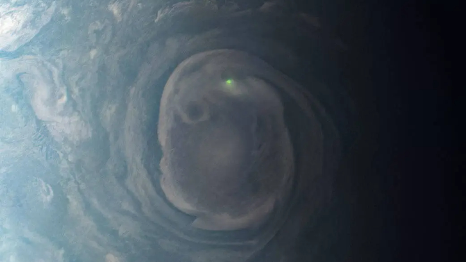 A close-up of a massive swirling storm on Jupiter with a green flash from a lightning bolt